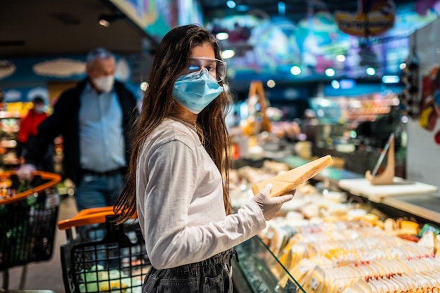 La niña con mascarilla quirúrgica va a comprar queso.