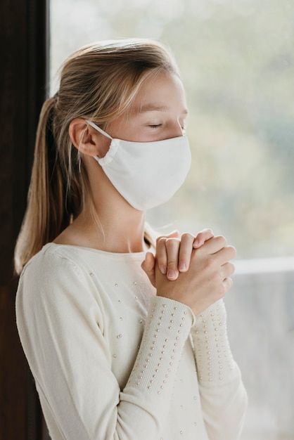 Niña con mascarilla rezando