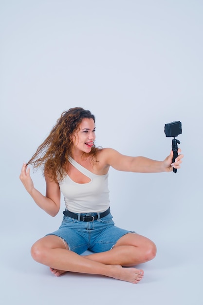 Foto gratuita niña con mimetismo divertido se está tomando selfie con su mini cámara sosteniendo el cabello