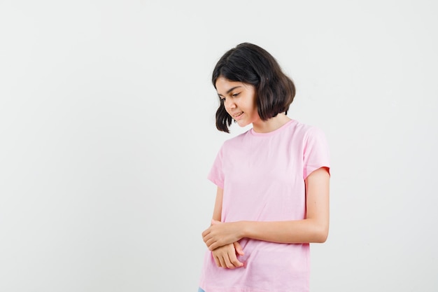 Niña mirando hacia abajo en camiseta rosa y muy bonita. vista frontal.