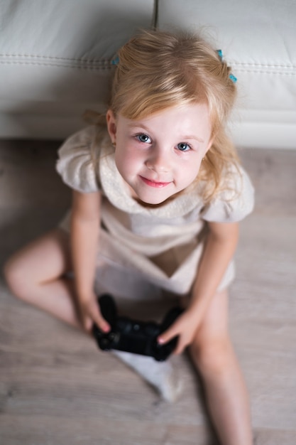 Niña mirando a la cámara jugando con joystick