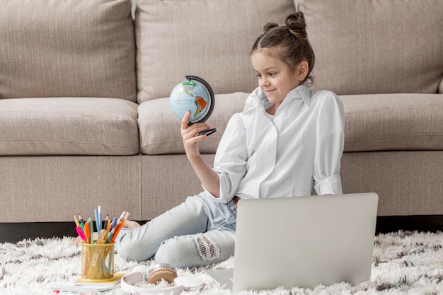 Foto gratuita niña mirando un globo terráqueo