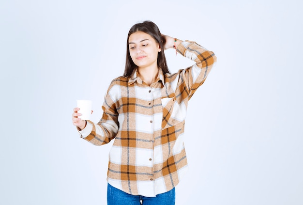 niña mirando una taza de té en la pared blanca.