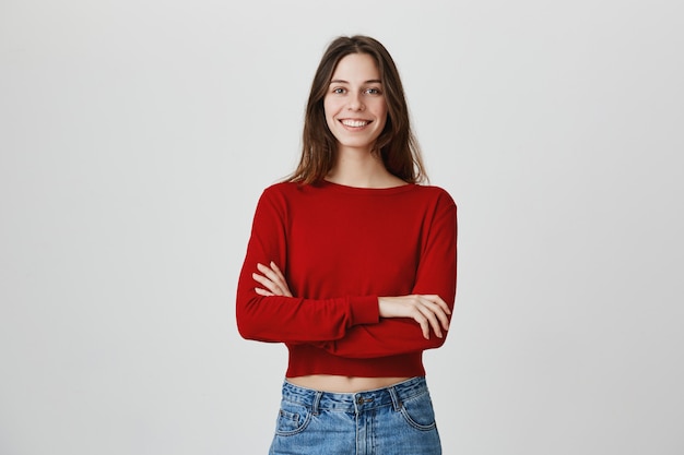 Foto gratuita niña morena confiada sonriente con las manos cruzadas sobre el pecho