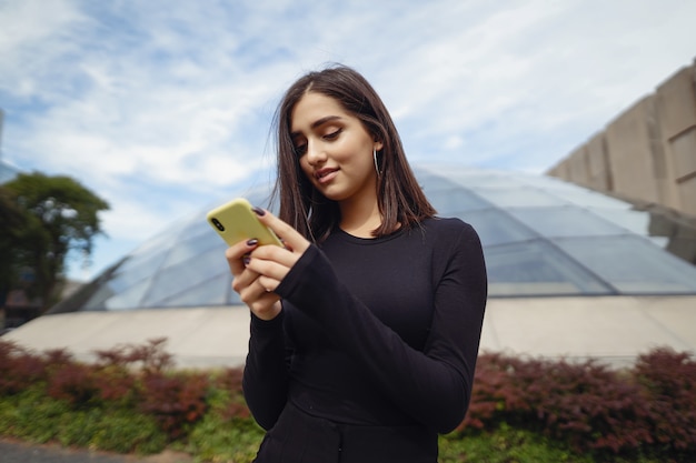 Niña morena usando su teléfono celular mientras explora una nueva ciudad