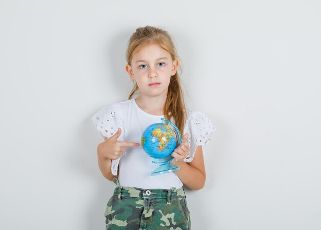 Niña mostrando en algún lugar del mundo en camiseta blanca