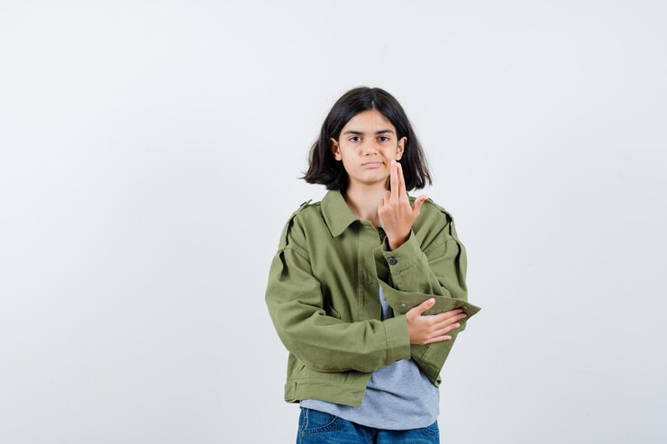 Foto gratuito niña mostrando gesto de pistola en abrigo, camiseta, jeans y mirando confiado, vista frontal.
