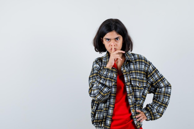 Niña mostrando gesto de silencio en camisa, vista frontal de la chaqueta. espacio para texto