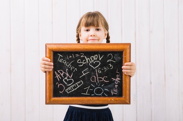 Niña mostrando pizarra con tiza pinturas