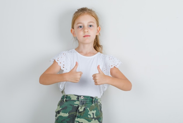 Niña mostrando los pulgares para arriba en camiseta blanca