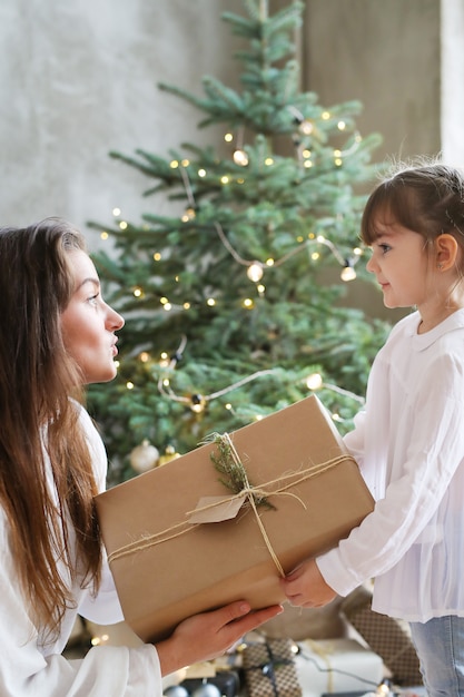 Niña y mujer con árbol de Navidad y presente