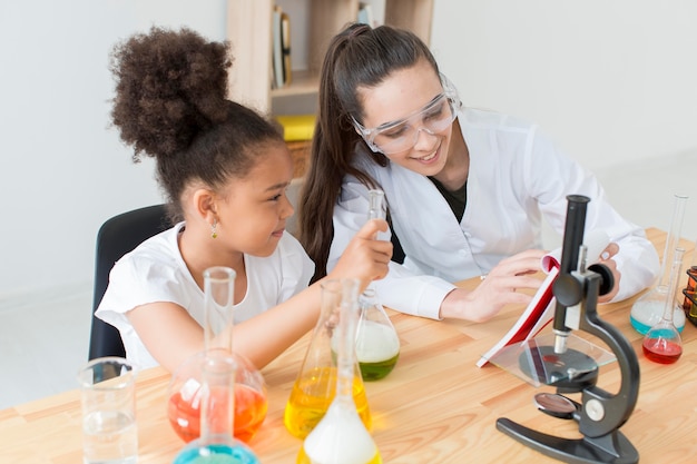 Niña y mujer científico divirtiéndose mientras aprende ciencia