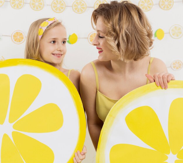 Niña y mujer mirando el uno al otro mientras sostiene la decoración de limón