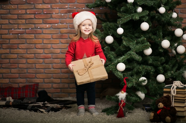Foto gratuita niña en navidad con caja de regalo por el árbol de navidad
