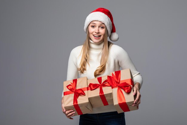 La niña de Navidad recibió un regalo. Sombrero de Santa aislado retrato de una mujer en una pared gris.