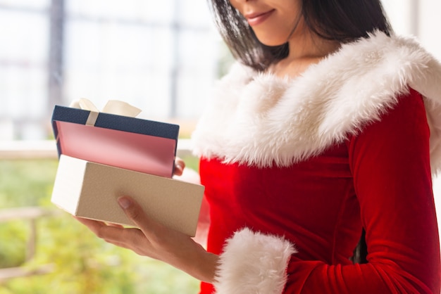 Niña de Navidad sonriente desenvolver caja de regalo azul