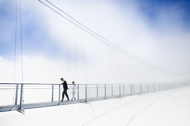 Niña y niño caminando sobre el puente en las nubes