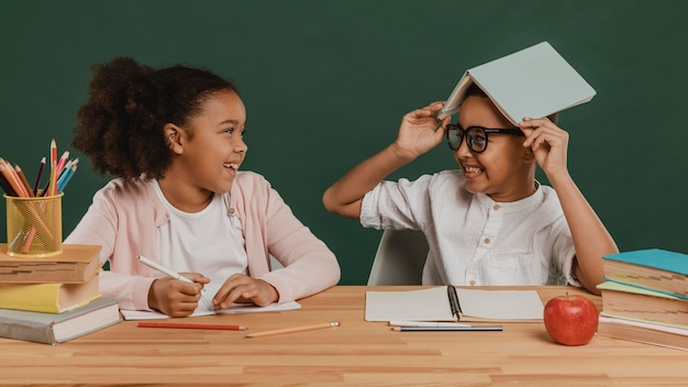 Foto gratuita niña y niño divirtiéndose con útiles escolares