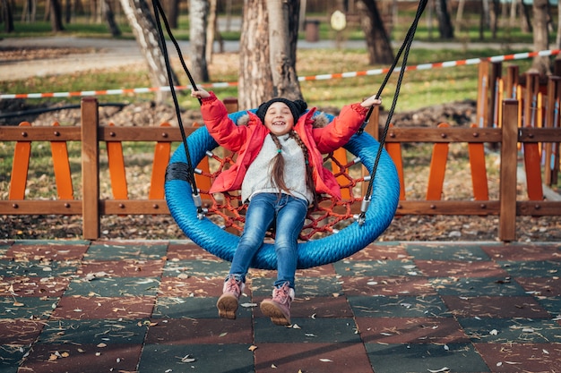 Niña niño feliz en columpio. Niño jugando en el paquete de otoño.