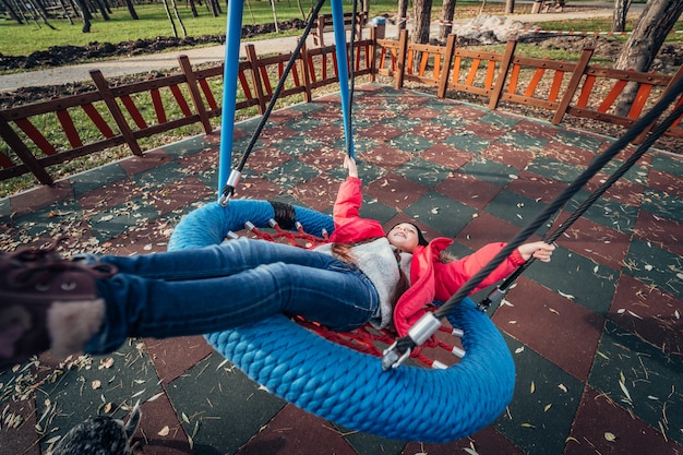 Foto gratuita niña niño feliz en columpio. niño jugando en el paquete de otoño.