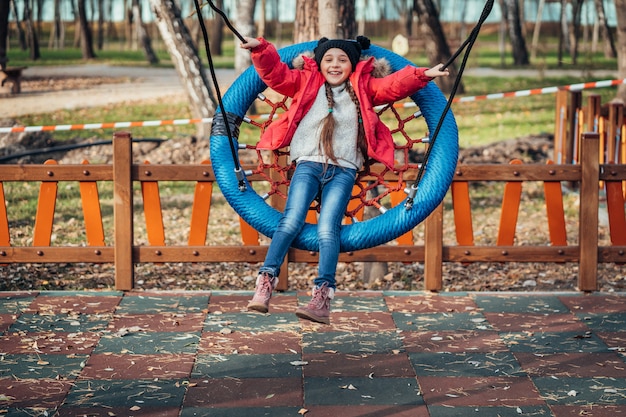 Foto gratuita niña niño feliz en columpio. niño jugando en el paquete de otoño.