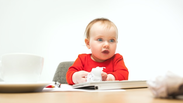 Niña niño feliz sentado con el teclado de la computadora moderna o portátil aislado en un estudio blanco