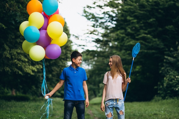 Niña y niño con globos en el parque