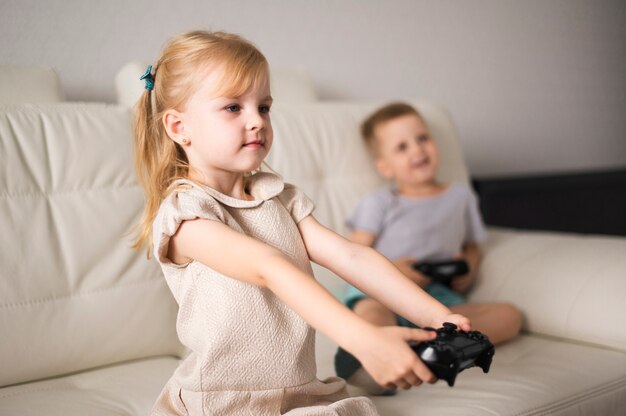 Niña y niño en el sofá con joystick