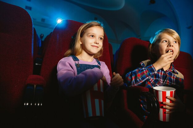 Niña y niño viendo una película en una sala de cine