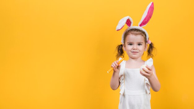 Niña en orejas de conejo con huevo y rotulador.