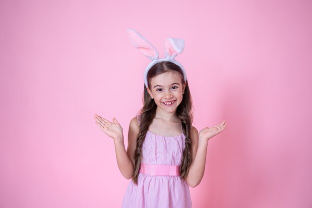 Niña con orejas de conejo de Pascua posando en rosa