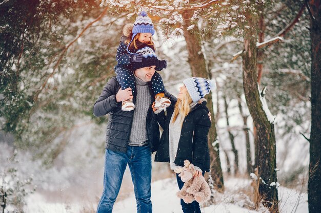 Niña con padres jugando en un parque de invierno