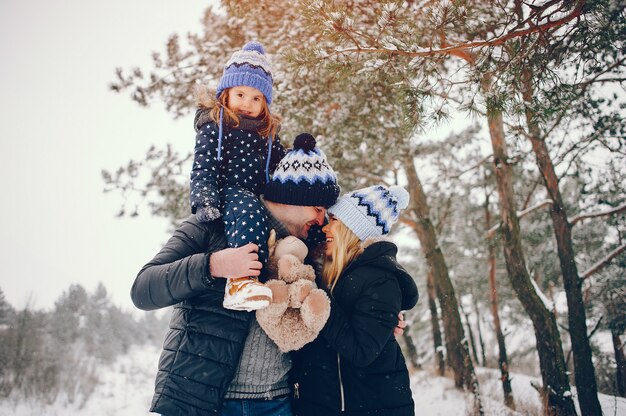 Niña con padres jugando en un parque de invierno