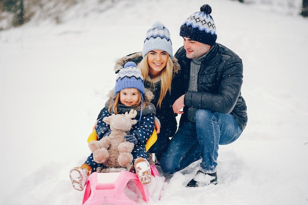 Niña con padres jugando en un parque de invierno