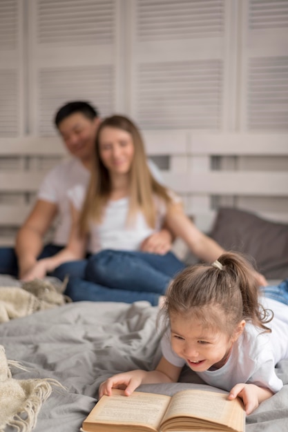 Foto gratuita niña con padres leyendo