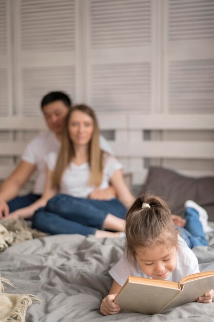 Foto gratuita niña con padres leyendo