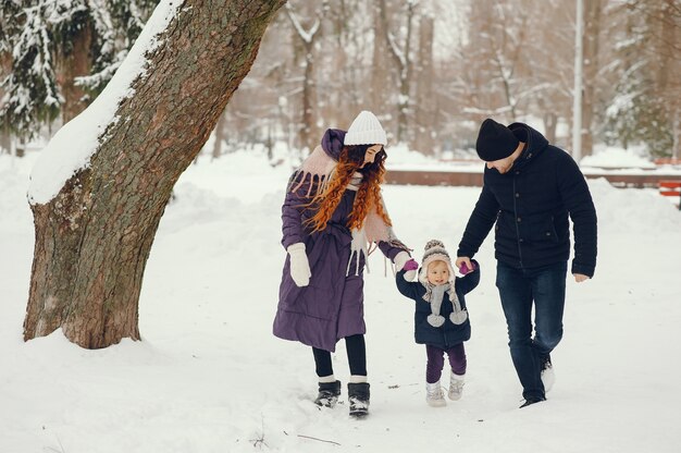 Niña con padres en un parque de invierno