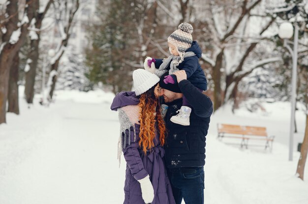 Niña con padres en un parque de invierno