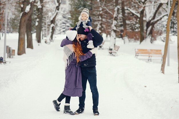 Niña con padres en un parque de invierno