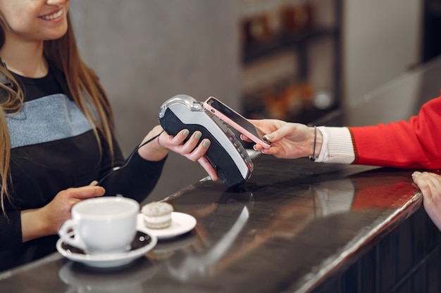 Niña pagando su café con leche con un teléfono inteligente con tecnología PAY PASS sin contacto