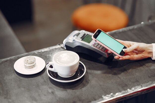Niña pagando su café con leche con un teléfono inteligente con tecnología PAY PASS sin contacto