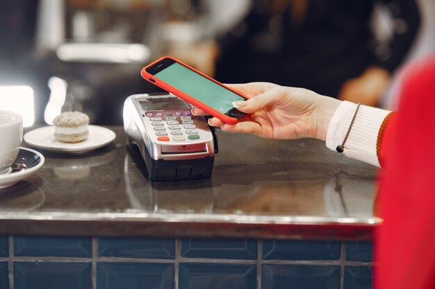 Niña pagando su café con leche con un teléfono inteligente con tecnología PAY PASS sin contacto