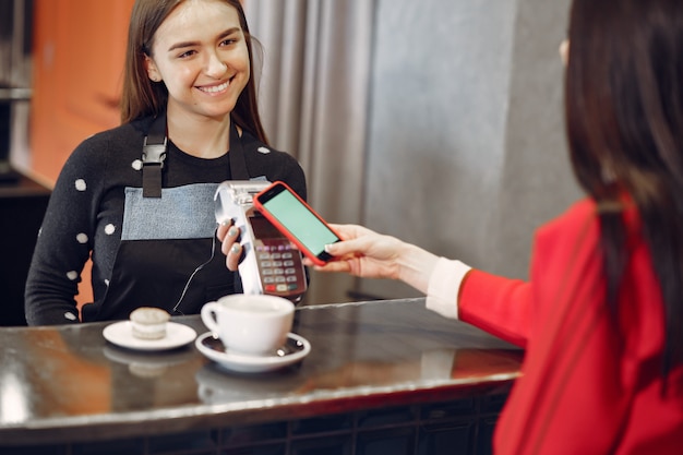 Niña pagando su café con leche con un teléfono inteligente con tecnología PAY PASS sin contacto