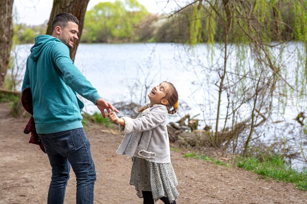 La niña y el papá están caminando por el bosque tomados de la mano.