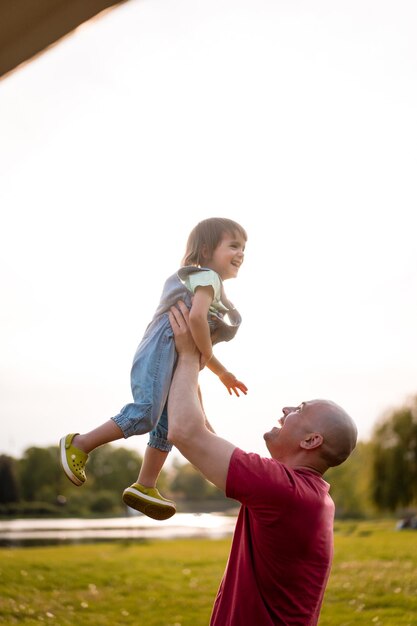 Niña con papá. Papá arroja al bebé al aire. Risa alegre, niño emocional, felicidad.