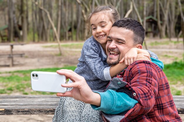 Una niña y un papá son fotografiados en la parte frontal del móvil en el parque a principios de la primavera.