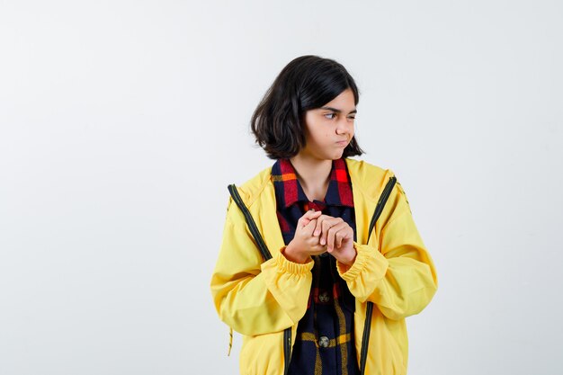 Niña parpadeando mientras mira hacia otro lado en camisa a cuadros, chaqueta y parece confiada