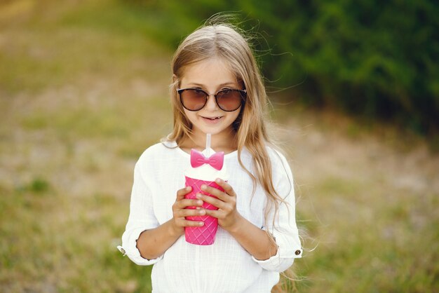 Niña en un parque de pie con copa rosa