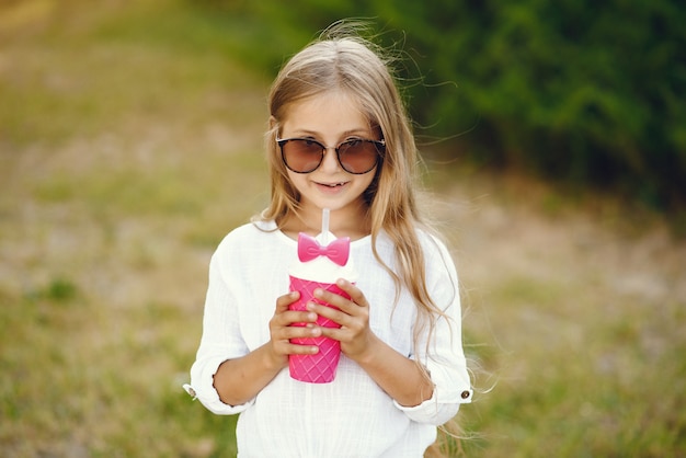 Niña en un parque de pie con copa rosa