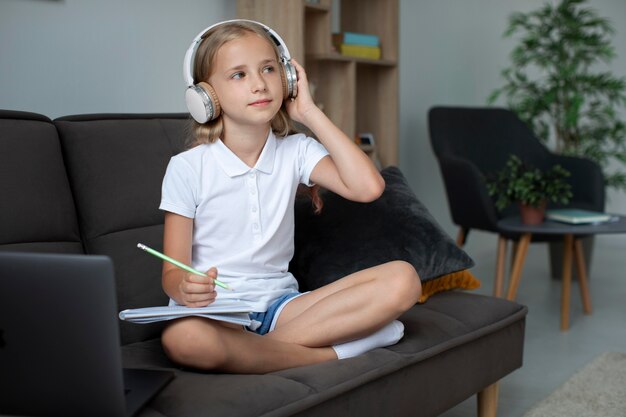 Niña participando en clases en línea mientras usa auriculares